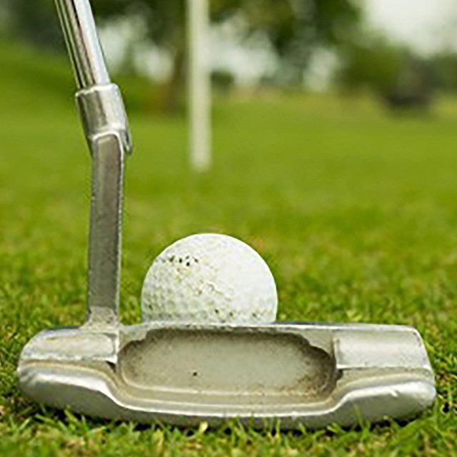 a putter and golf ball on bright green grass