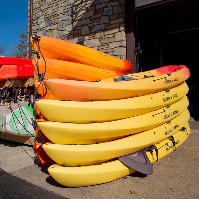 colorful kayaks, canoes and paddleboards stacked on a dock