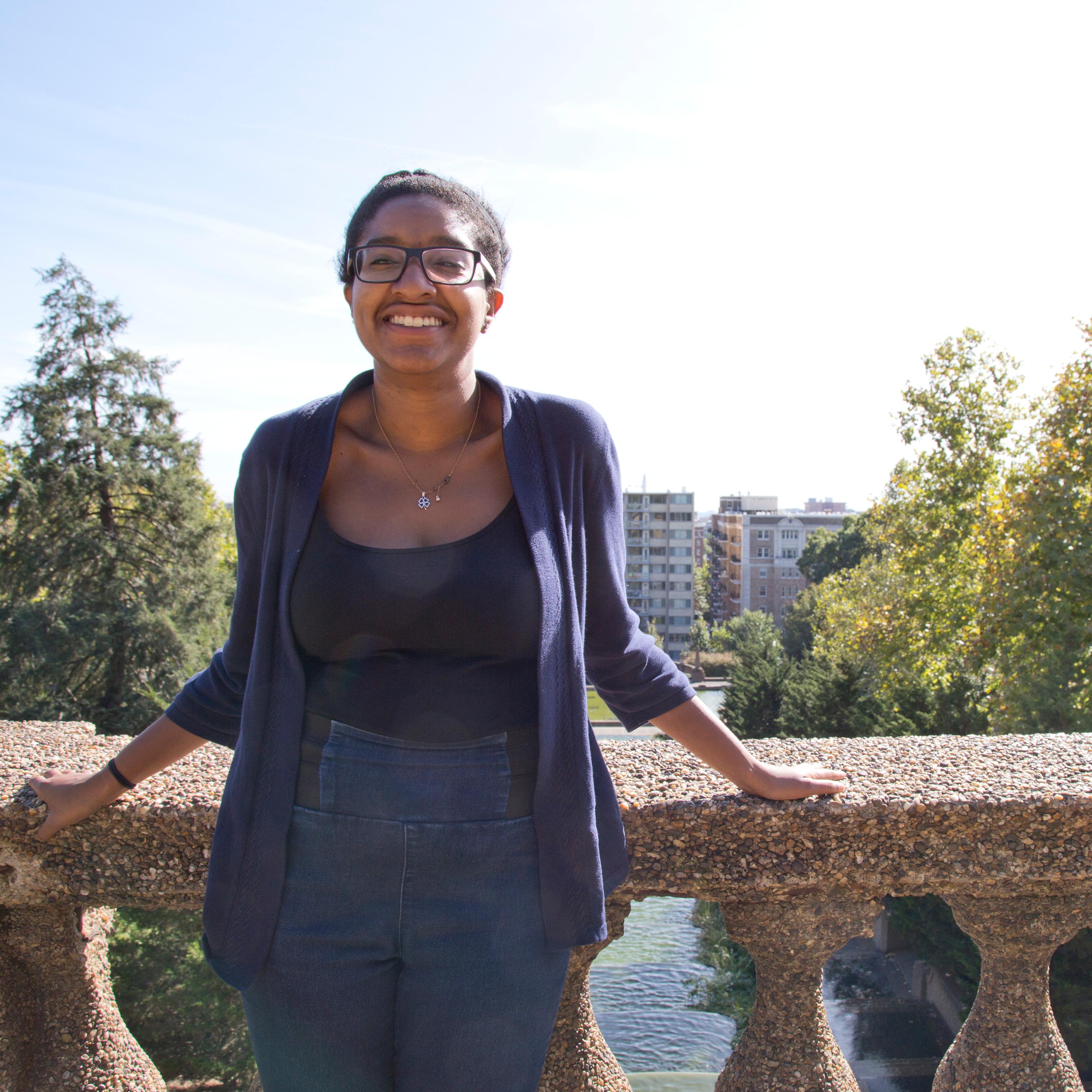 A young woman smiles as she stands on the top level of Meridian Hill Park. 
