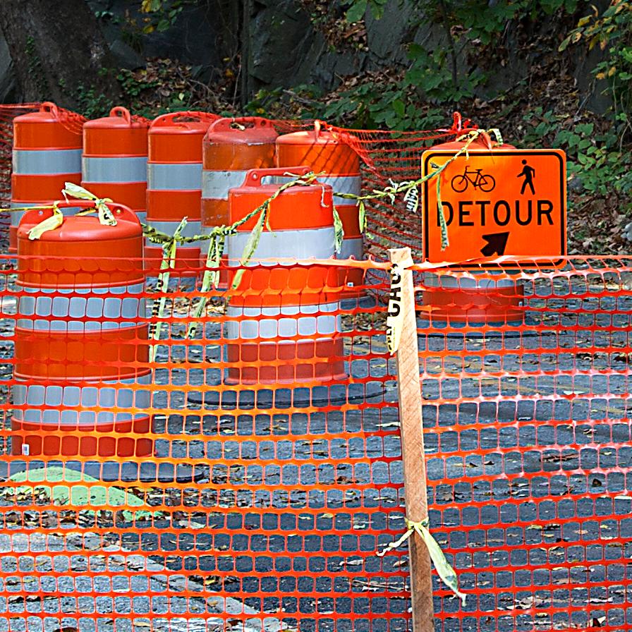 A road has bright orange barrels blocking the way. 