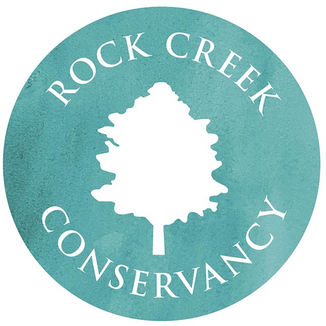 A teal logo with a tree and Rock Creek Conservancy around outside of circle