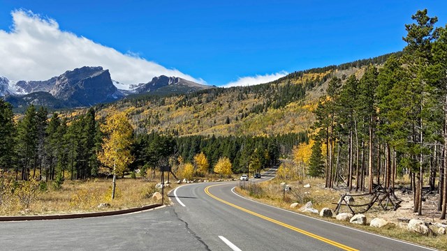 A vehicle is driving on Bear Lake Road with the mountains in the distance in fall