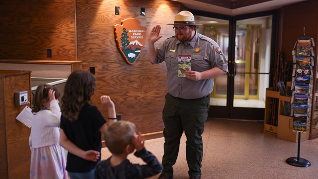 A Park Ranger is swearing in three new Junior Rangers