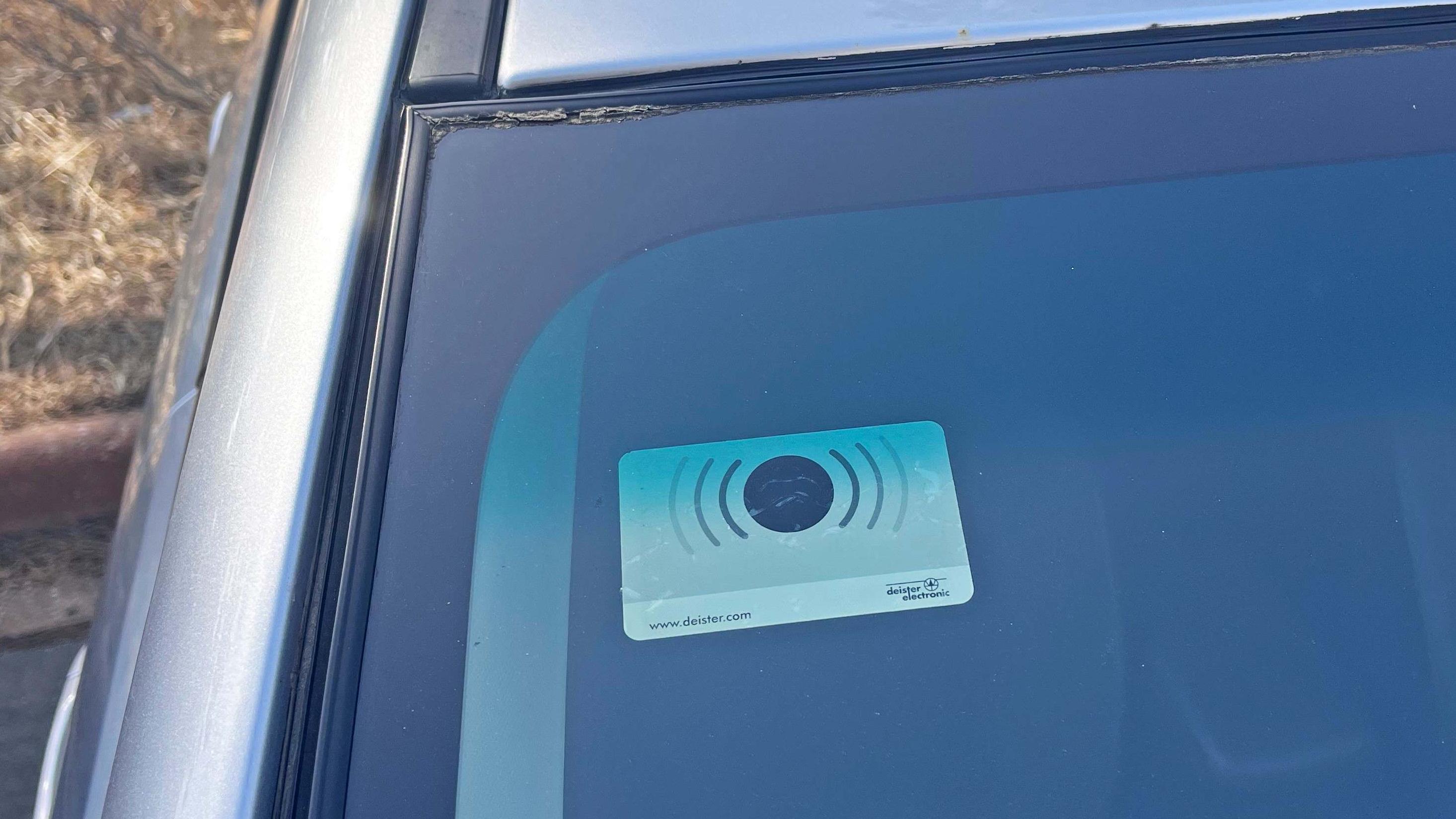 A transponder is affixed on the top passenger side of a windshield.