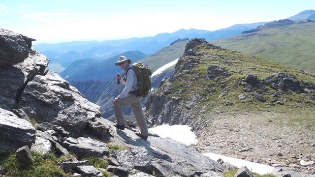 A person is wearing sun protective clothing while hiking in the alpine
