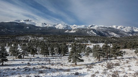 Mountains along the Continental Divide are covered in snow, the valleys and trees are also snowy