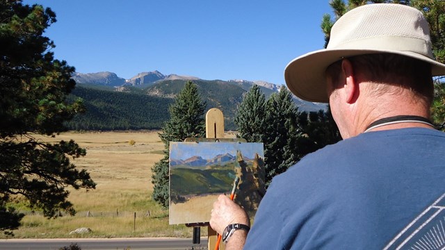 An artist-in-residence is seen painting a scene near Moraine Park