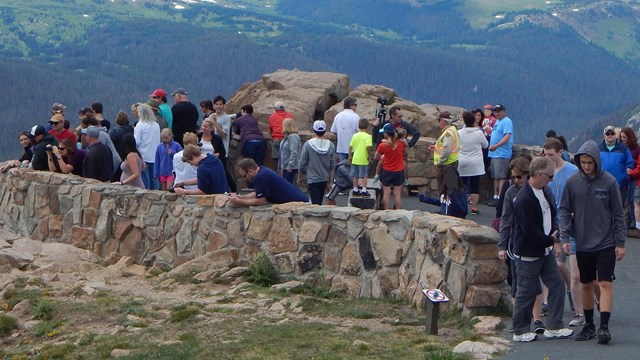 A large crowd of visitors are clustered together at the Bear Lake Trailhead on a typical summer say