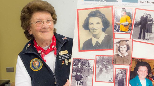 Older woman with curly hair and glasses holds a homemade poster with photos of herself.