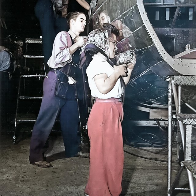 Two men and a small woman are working. The woman is working on a plance. 