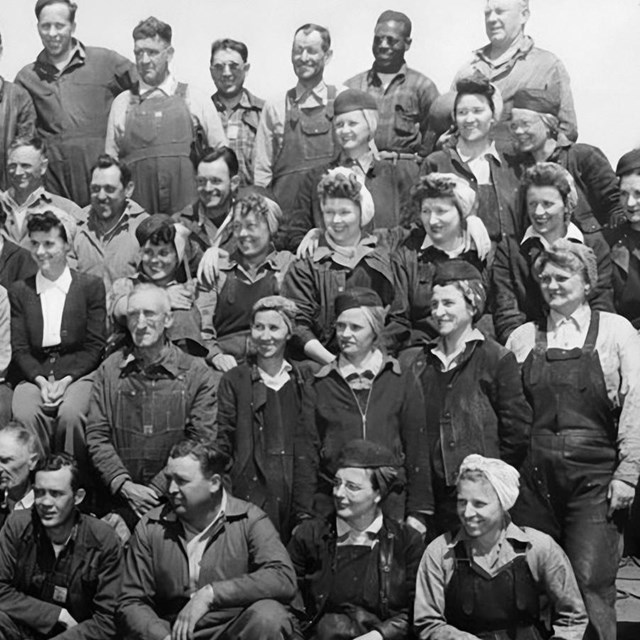 A diverse group of shipyard workers posing for a group photo. 