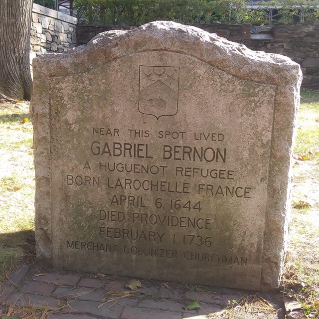 Stone plaque along walkway with text that remembers Gabriel Bernon and his connection to this site.