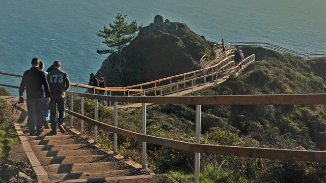People walk up and down a series of steps as the sun rises on the Muir Beach Overlook, a trail with