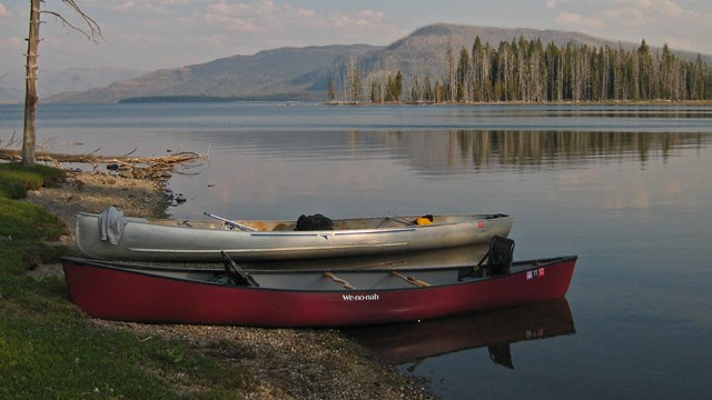 Two canoes docked by a lake