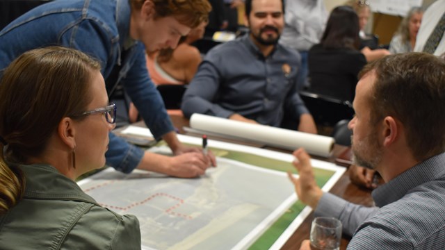 National Park Service staff and partners draw a potential trail on a map during a community meeting.