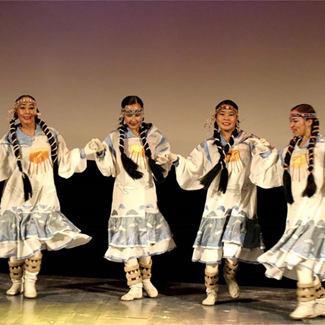 4 девушки в национальных костюмах танцуют на сцене