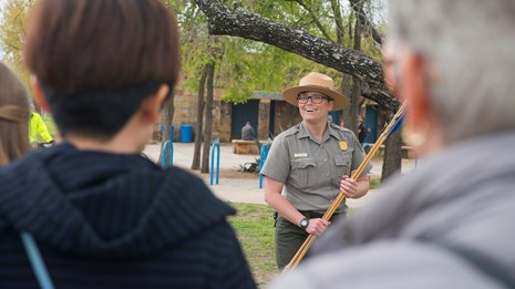 Park Ranger holds an atl atl as she gives presentation to elementary school students