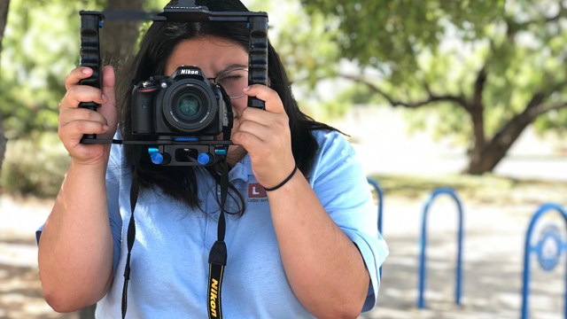 Latino Heritage Intern holding a camera up to her face.