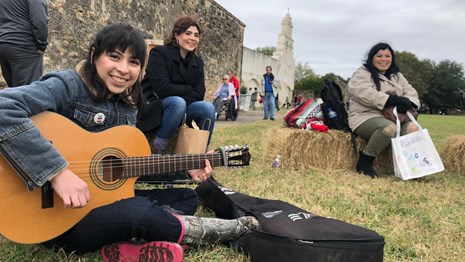 Woman plays acoustic guitar at Mission San Jose.