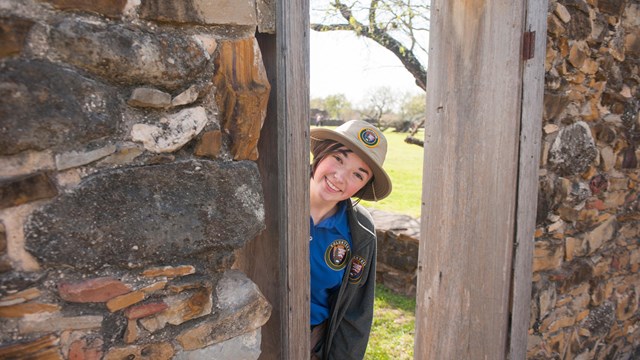 Youth volunteer peeks through historic door at Mission San Jose