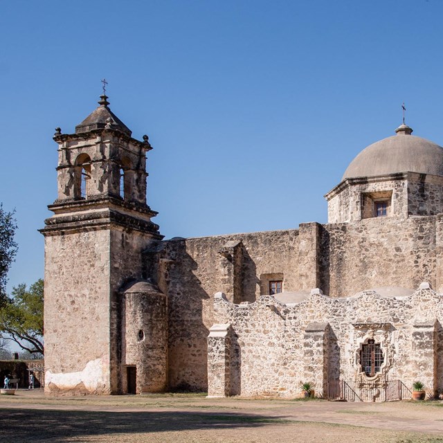 large stone church with yucca plant in the forground