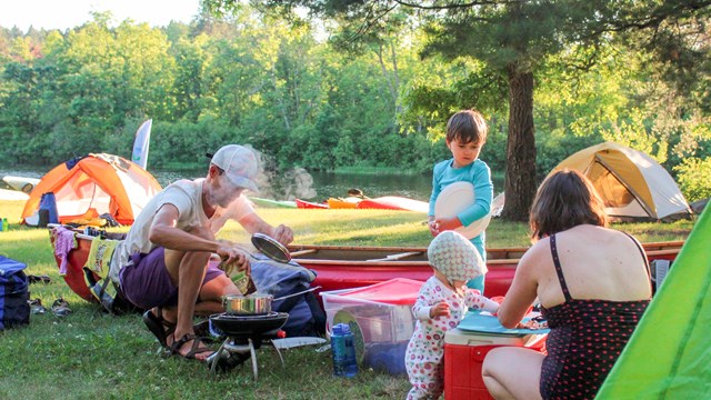 A family cooks outdoors at their campsite,