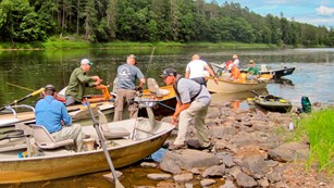 People prepare to launch boats on a river.