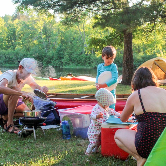 A family cooks outdoors at their campsite,