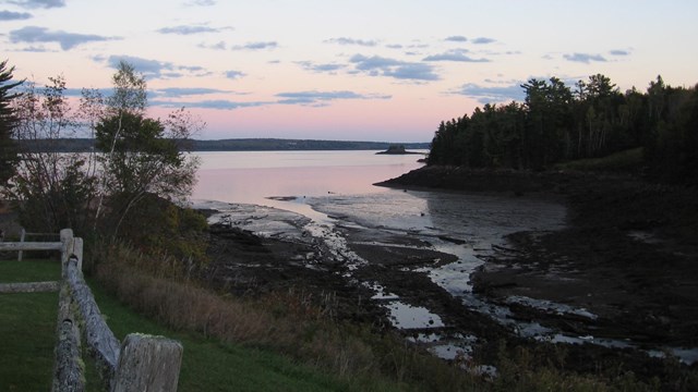 a sunrise over a cove with the tide going out