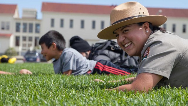 a ranger in the grass with student; golden gate bridge in the background