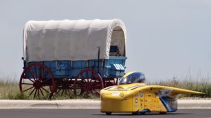 A solar car next to a wagon.