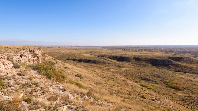 A rocky bluff, looking out over a vast plain.