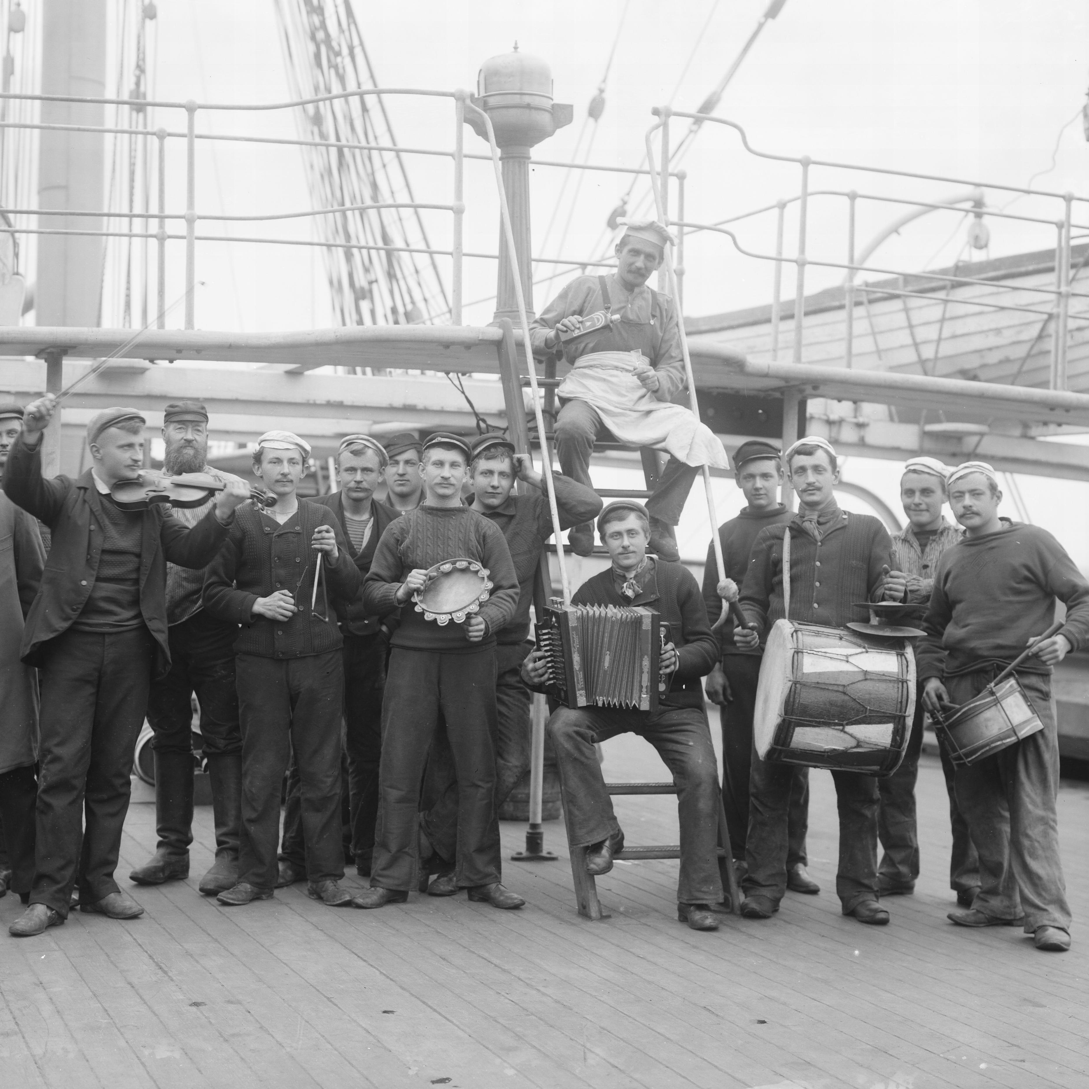 Group of men standing on the deck of a sailing ship holding various instruments