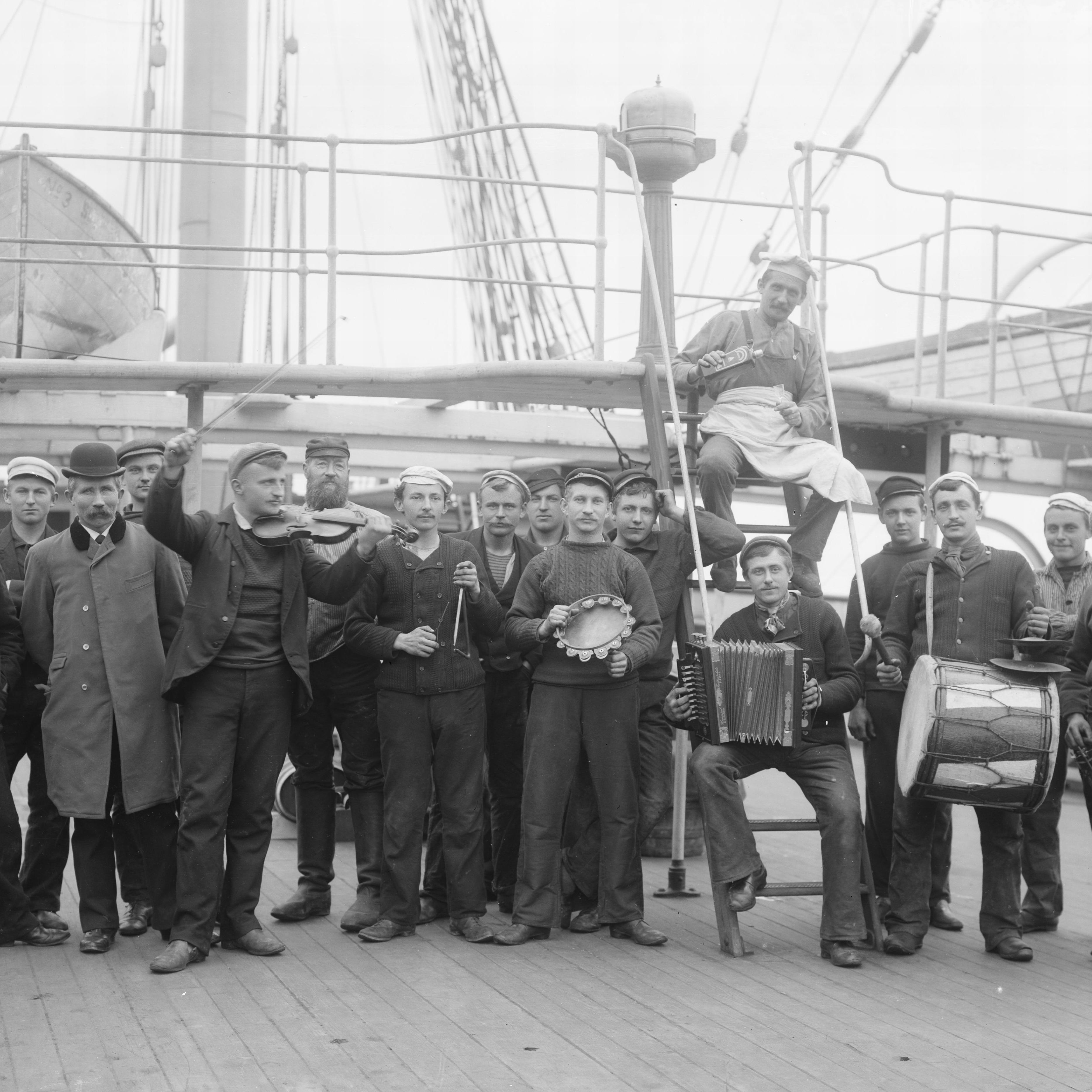 black and white image of men holding instruments standing on the deck of a ship.