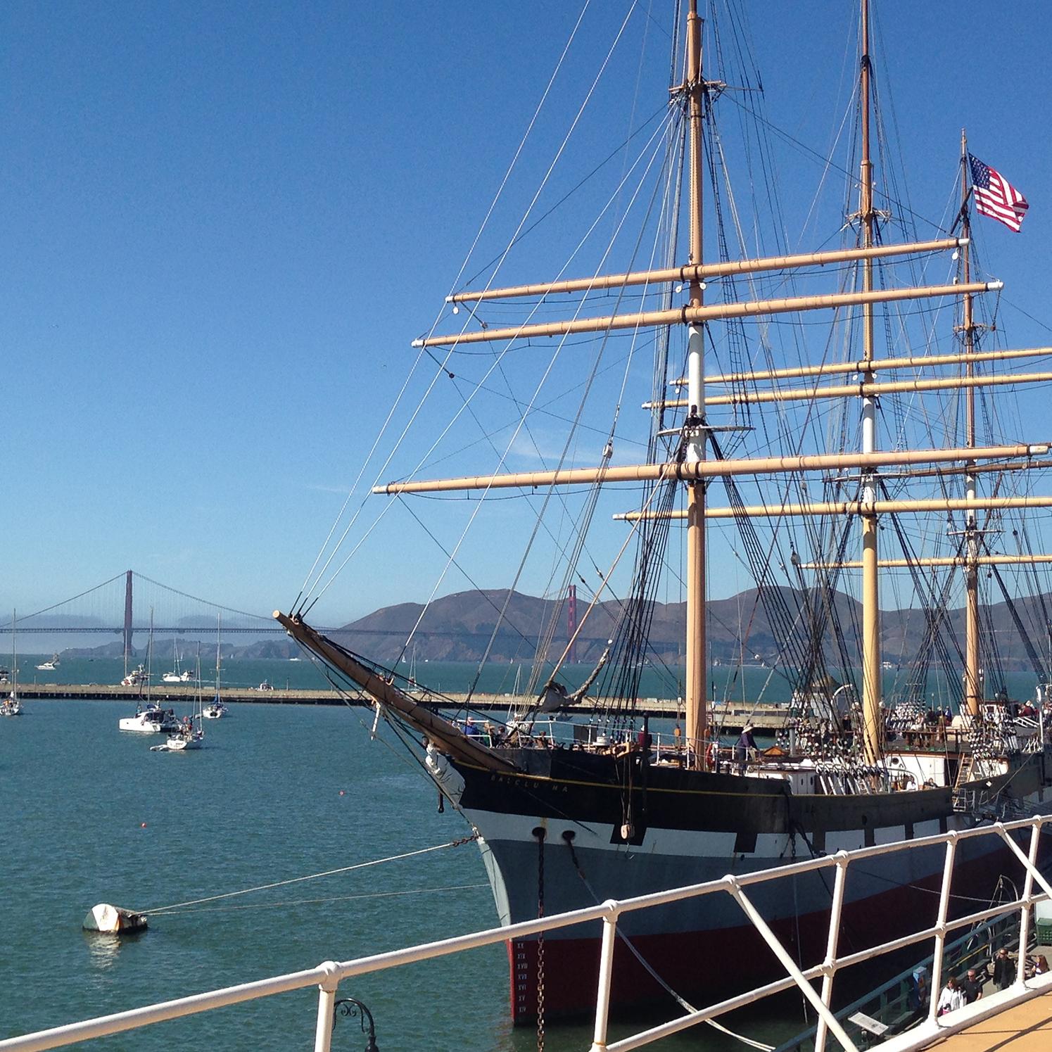 A restored historic sailing ship built in 1886 moored along a pier.
