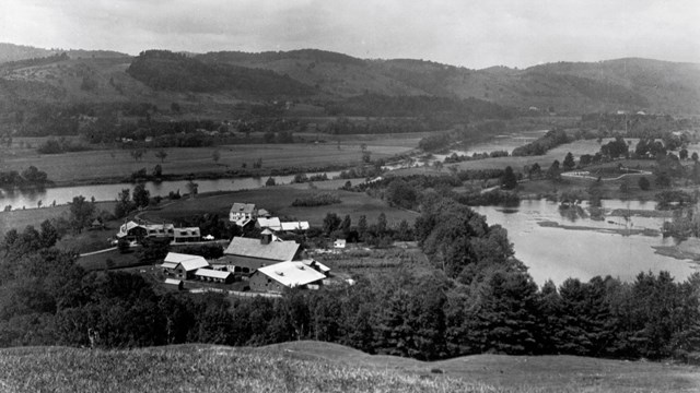 black and white photo of farm along river