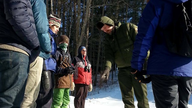 People looking at animal tracks with ranger