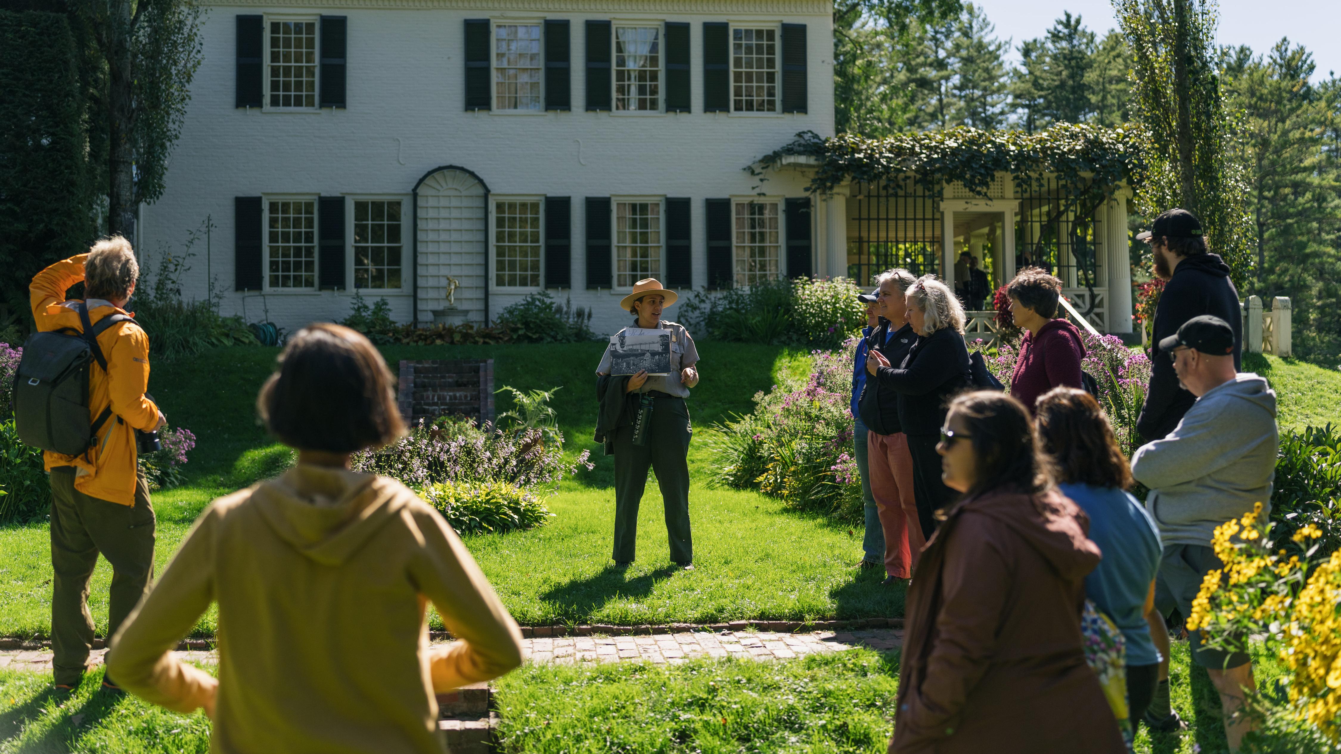 Park Ranger and group of people talk in front of historic home