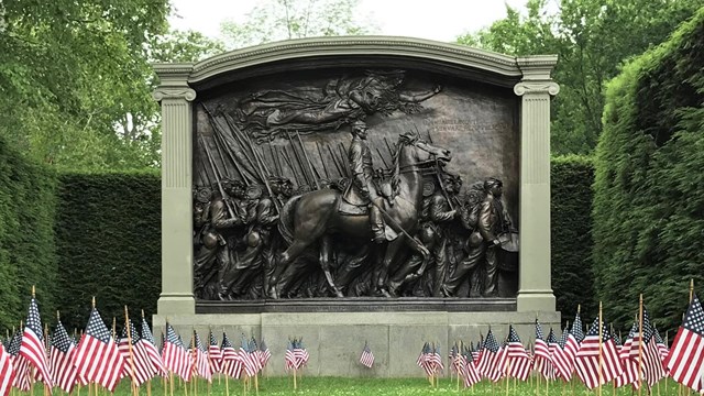 Civil War memorial behind small American flags in ground