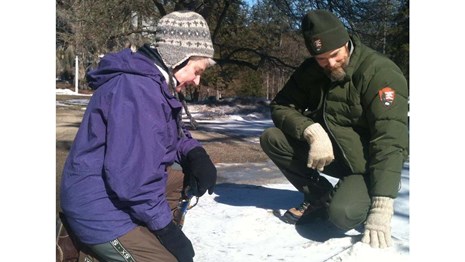Ranger and program participant examine tracks in the snow