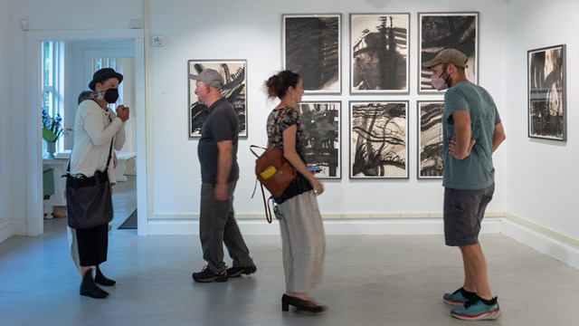people mingle in gallery with art hung on walls