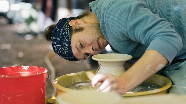 person shapes clay on a pottery wheel