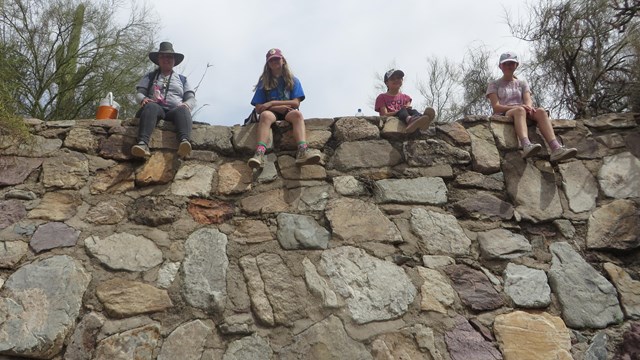 kids sitting atop a tall rock dam