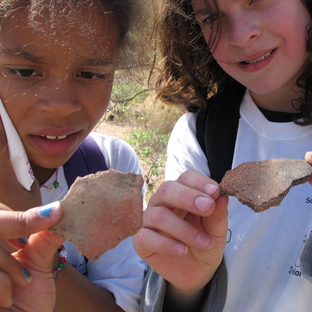 two kids holding pottery sherds