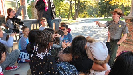 A park ranger interacting with young students on the porch of the Roosevelt Home.