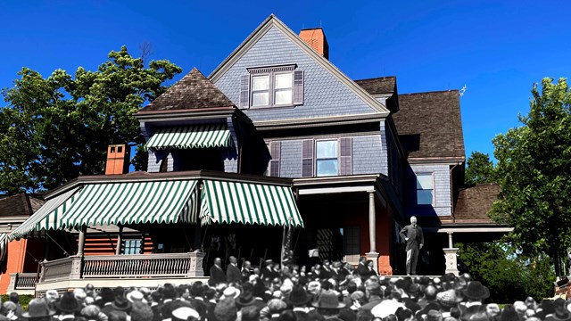 Theodore Roosevelt on his porch with a crowd below.