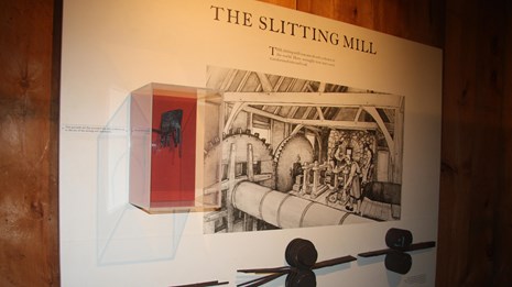 exhibit display with image of people working in slitting mill and artifacts from the mill