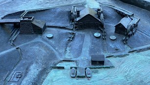 a tactile scaled metal sculpture of the park lower level with four buildings and dock with two boats