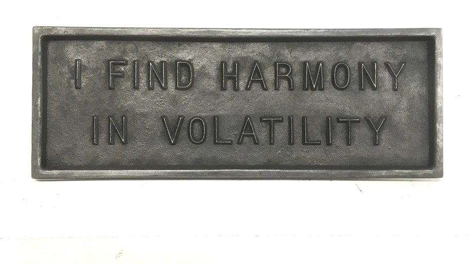 Iron plaque with raised text reading "I find harmony in volatility"