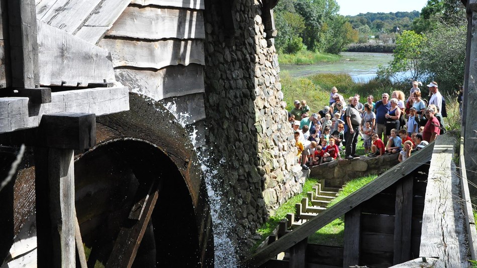 Visitors watch a waterwheel turning